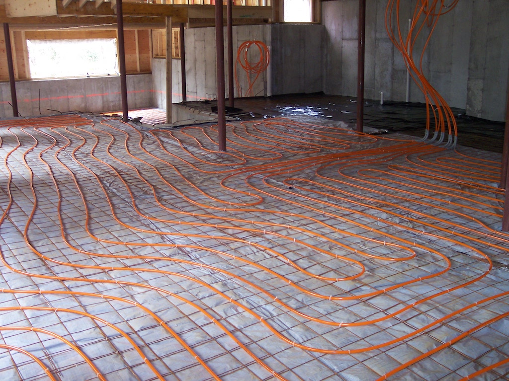 Orange PEX tubing laid in loops for hydronic radiant floor heating before concrete pour