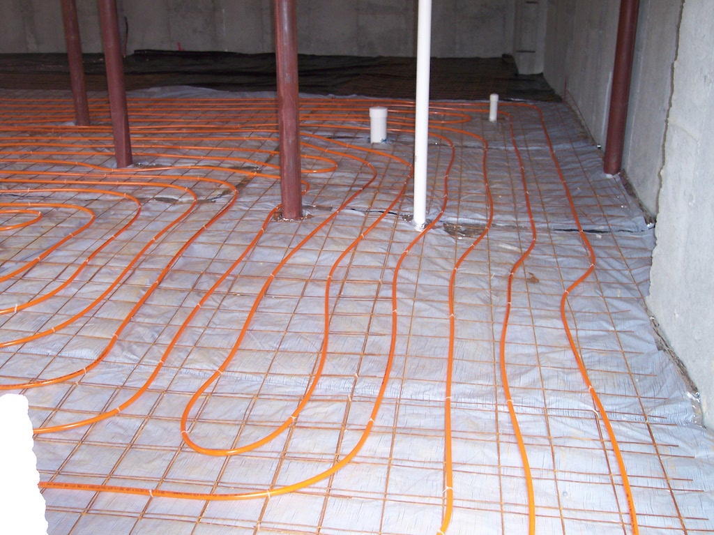 Radiant floor heating tubing secured to wire mesh over a reflective vapor barrier