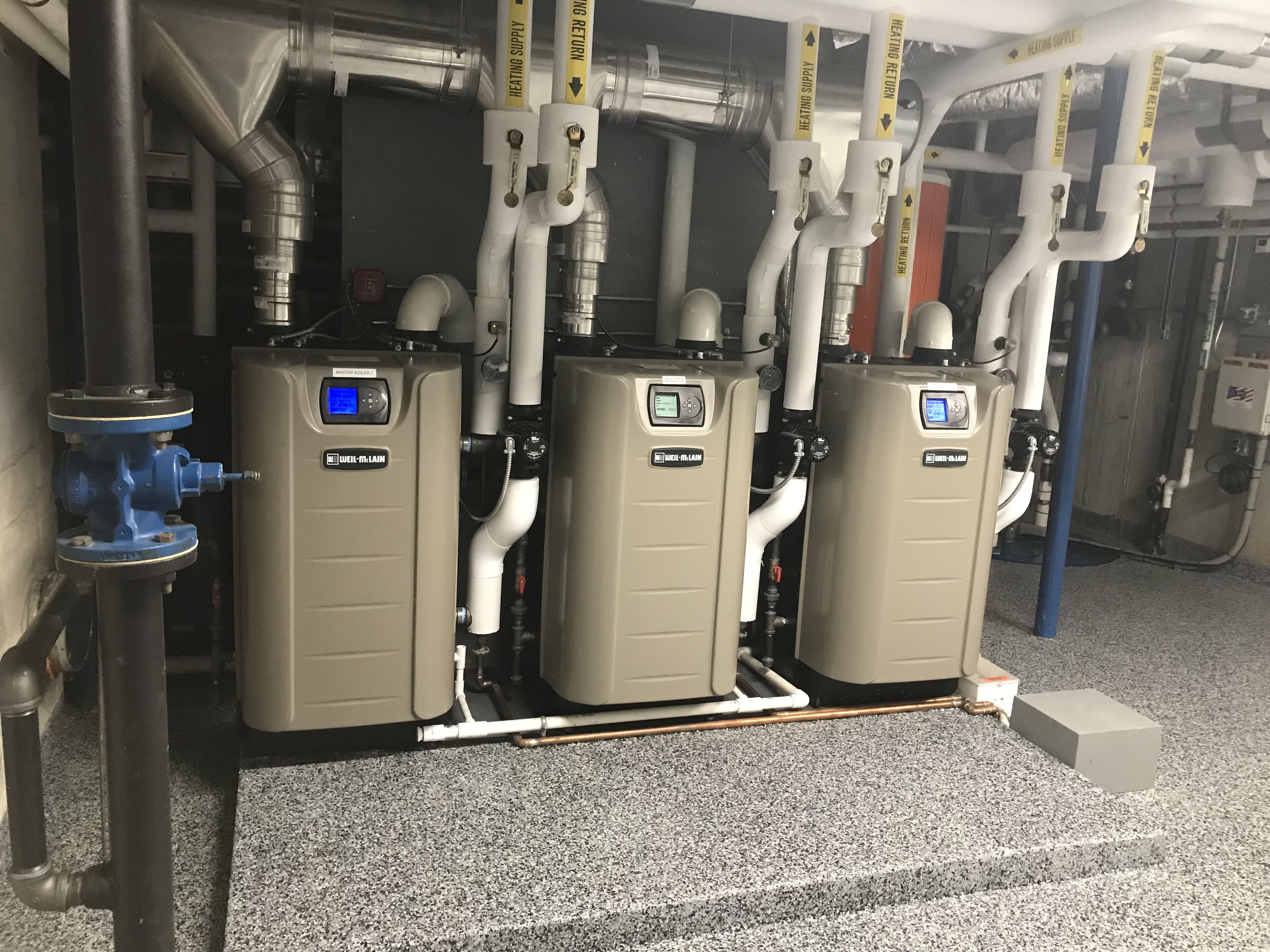 Three Weil-McLain commercial boilers with labeled heating supply and return piping
