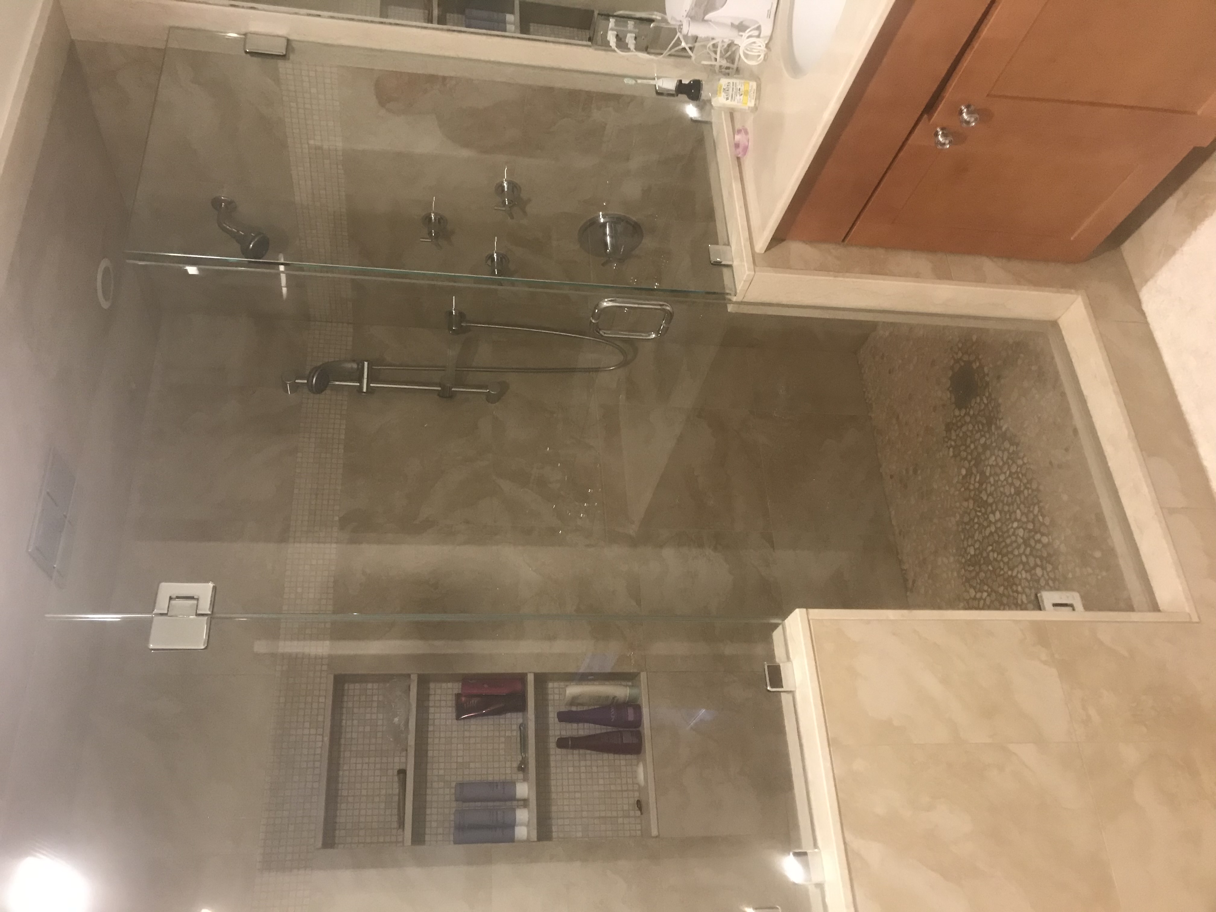Glass-enclosed shower with pebble floor, built-in bench, and mosaic accent band