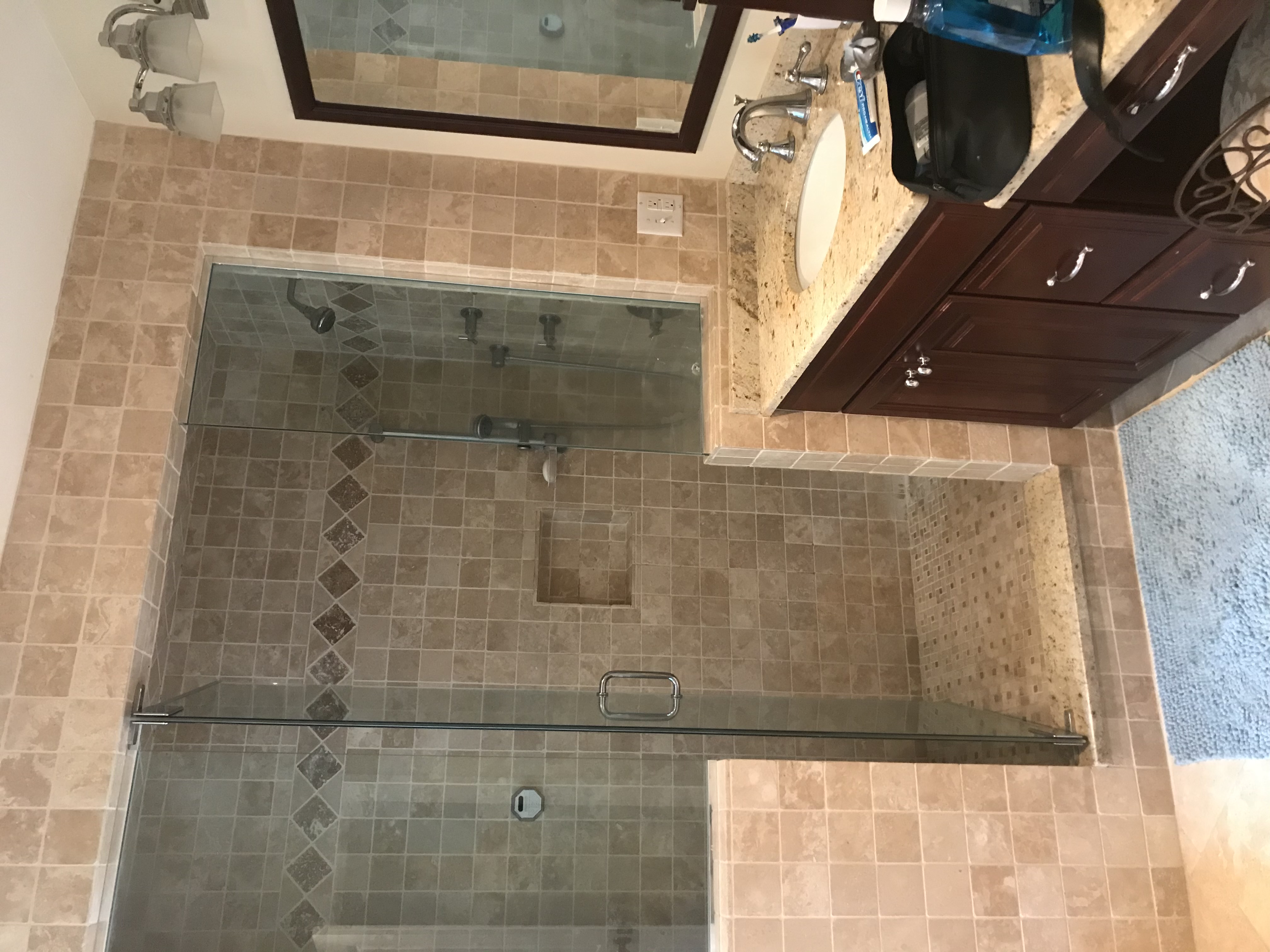 Renovated bathroom with tan-tile walk-in shower and dark wood vanity with granite top