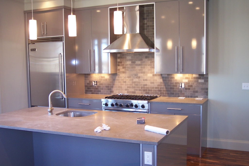 Modern kitchen with stainless steel appliances, island sink, and professional range hood